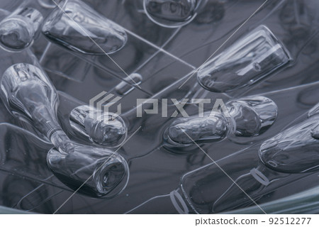 Glass medical ampoule vial for injection. Medicine is liquid sodium chloride with of aqueous solution in ampulla. Close up. Bottles ampule multicolor. Glass medical ampoule vial for injection. Medicine is liquid sodium chloride with of aqueous solution in ampulla. Close up. Bottles ampule multicolor. 92512277
