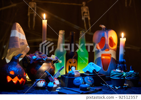 Halloween pumpkins with burning mouths, candles, drinks and sweets. 92512357