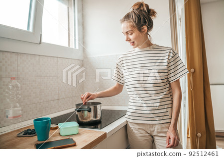 Cheerful housewife cooking breakfast in the morning Cheerful housewife cooking breakfast in the morning 92512461