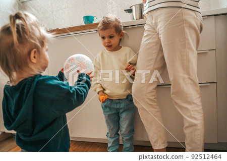 Two children and an adult person in the kitchen Two children and an adult person in the kitchen 92512464