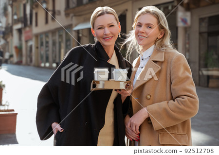 Joyful elegant women posing for the camera in the street Joyful elegant women posing for the camera in the street 92512708