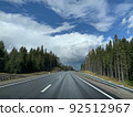 Road among the hills and woodlands under an overcast sky Road among the hills and woodlands under an overcast sky 92512967