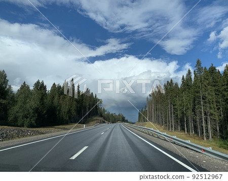 Road among the hills and woodlands under an overcast sky 92512967