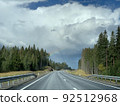 Road among the hills and woodlands under an overcast sky Road among the hills and woodlands under an overcast sky 92512968
