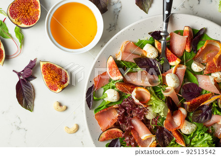 Freshly made Chopped Salad in Italian restaurant, mozzarella, figs, prosciutto or jamon. White marble background Freshly made Chopped Salad in Italian restaurant, mozzarella, figs, prosciutto or jamon. White marble background 92513542