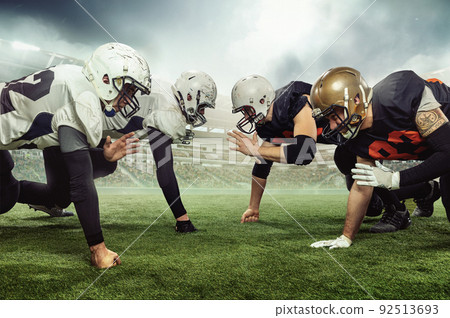 Professional male american football players getting ready to start game during sport match on sky background at stadium with flashlights. Collage 92513693