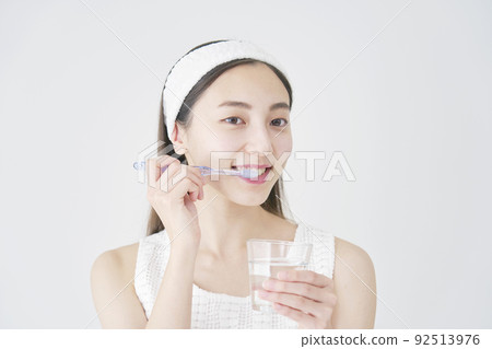 一個女人用白色背景上的玻璃刷牙 92513976