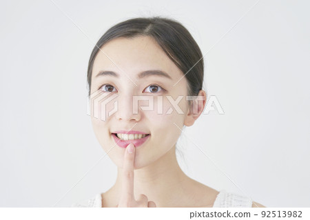 一個女人用白色背景指著她的嘴 92513982