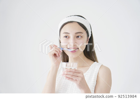 一個女人用白色背景上的玻璃刷牙 92513984