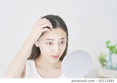 A woman checking her hair in the mirror in the living room 92513985