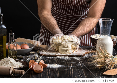 Against the background of men's hands knead the dough. Ingredients for cooking flour products or dough bread, muffins, pie, pizza dough . 92514796