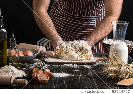 Against the background of men's hands knead the dough. Ingredients for cooking flour products or dough bread, muffins, pie, pizza dough . Against the background of men's hands knead the dough. Ingredients for cooking flour products or dough bread, muffins, pie, pizza dough . 92514797