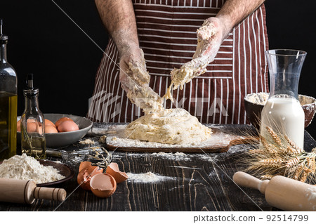 Against the background of men's hands knead the dough. Ingredients for cooking flour products or dough bread, muffins, pie, pizza dough . 92514799