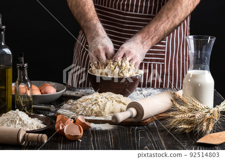 Against the background of men's hands knead the dough. Ingredients for cooking flour products or dough bread, muffins, pie, pizza dough . 92514803