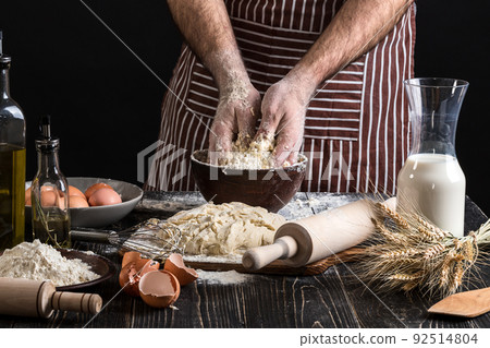 Against the background of men's hands knead the dough. Ingredients for cooking flour products or dough bread, muffins, pie, pizza dough . 92514804
