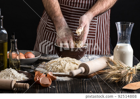 Against the background of men's hands knead the dough. Ingredients for cooking flour products or dough bread, muffins, pie, pizza dough . 92514808