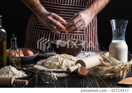 Cook accurately breaks the egg to make dough. 92514817