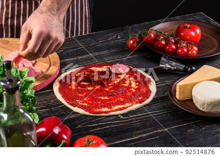 Cook in the kitchen putting the ingredients on the pizza. Pizza concept. Production and delivery of food. Cook in the kitchen putting the ingredients on the pizza. Pizza concept. Production and delivery of food. 92514876