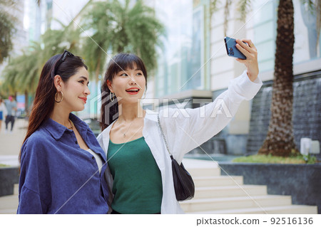 Happy two young women taking selfie on city street. 92516136