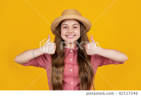 happy child in straw hat on yellow background. thumb up happy child in straw hat on yellow background. thumb up 92517248