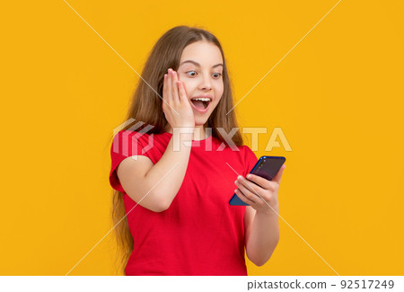amazed girl with smartphone on yellow background 92517249