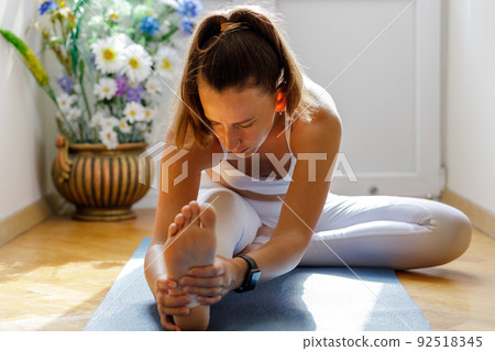 Young woman stretching legs during her morning yoga training 92518345