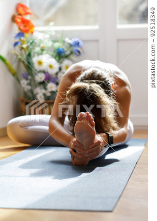 Young woman stretching legs during her morning yoga training 92518349