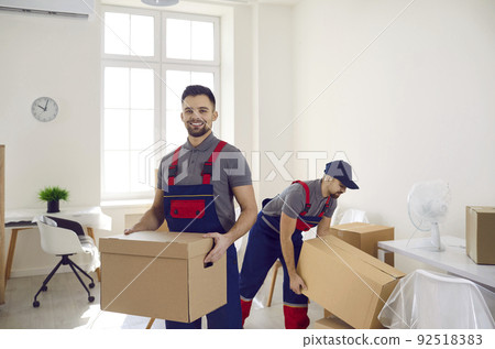 Smiling deliverymen working with packages at client home Smiling deliverymen working with packages at client home 92518383