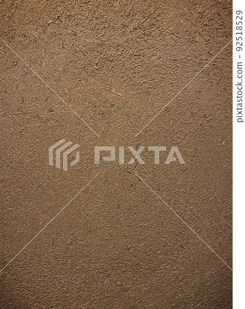 Vertical background image of the surface where the rough texture of straw remains in the dark brown clay wall Vertical background image of the surface where the rough texture of straw remains in the dark brown clay wall 92518529