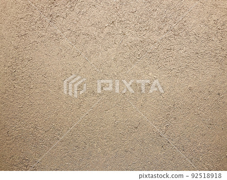 Horizontal background image of the surface where the rough texture of straw remains in the light brown clay wall 92518918
