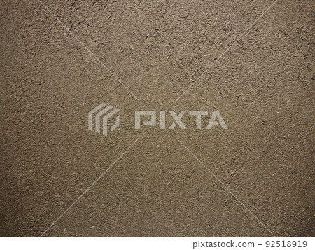 Horizontal background image of the surface where the rough texture of straw remains in the dark light brown soil wall 92518919