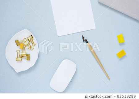 Workplace of a blogger, artist, or calligrapher. A sheet of white paper, a fountain pen, a mouse, a notebook, a glider or a diary and watercolour paints in ditches Workplace of a blogger, artist, or calligrapher. A sheet of white paper, a fountain pen, a mouse, a notebook, a glider or a diary and watercolour paints in ditches 92519289