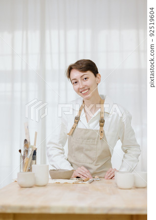woman ceramist in the workshop makes mugs out of clay. small business or hobby is the creation of ceramic products woman ceramist in the workshop makes mugs out of clay. small business or hobby is the creation of ceramic products 92519604
