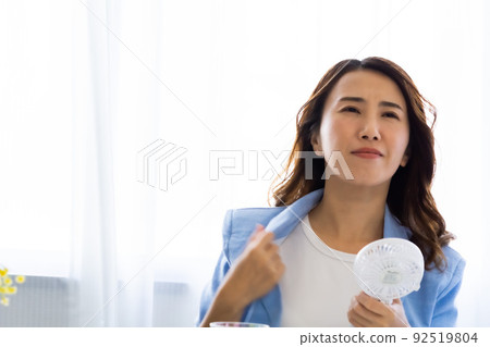 A woman who cools off with a fan 92519804