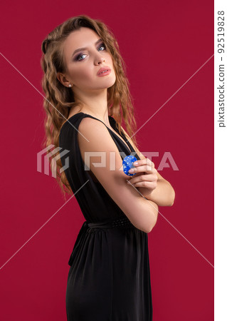 Portrait of the female gambler at the casino keeping poker chips in the hand Portrait of the female gambler at the casino keeping poker chips in the hand 92519828