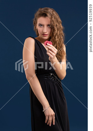 Portrait of the female gambler at the casino keeping poker chips in the hand Portrait of the female gambler at the casino keeping poker chips in the hand 92519939