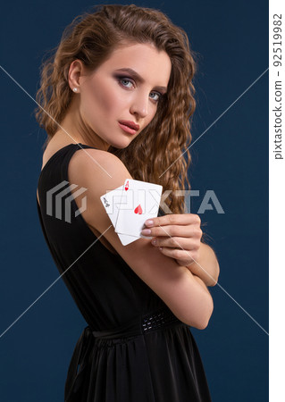Beautiful brunette holding two aces as a sign for poker game, gambling and casino 92519982