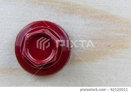 Close-up of the head of a red roofing self-tapping screw in a wooden board. Close-up of the head of a red roofing self-tapping screw in a wooden board. 92520011