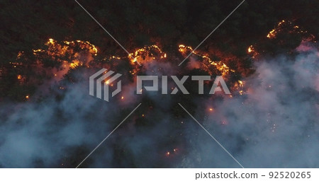Aerial panoramic view of a forest fire at night, heavy smoke causes air pollution, and fire in full blaze. Natural disaster epic drone cinematic shot. Aerial panoramic view of a forest fire at night, heavy smoke causes air pollution, and fire in full blaze. Natural disaster epic drone cinematic shot. 92520265