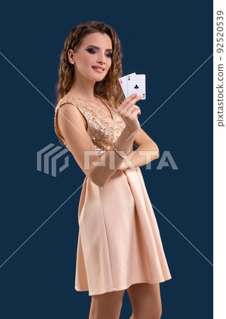 Young beautiful woman holding the winning combination of poker cards on dark blue background. Two aces 92520539