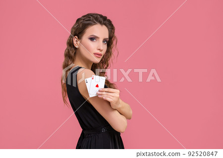 Young woman holding two aces in hand against on pink background Young woman holding two aces in hand against on pink background 92520847