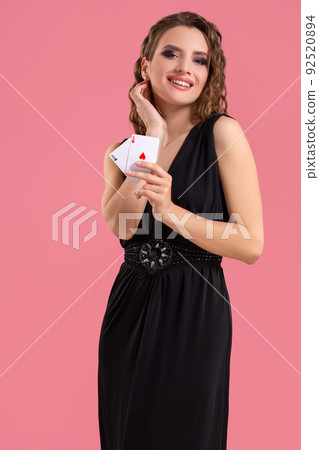 Young woman holding two aces in hand against on pink background Young woman holding two aces in hand against on pink background 92520894