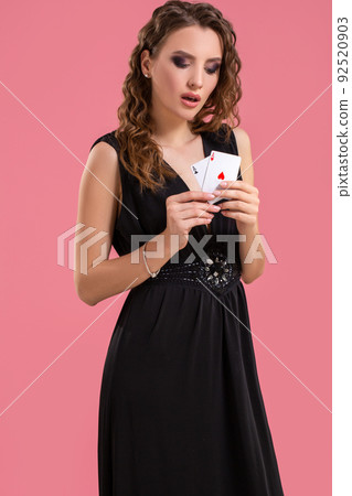 Young woman holding two aces in hand against on pink background 92520903