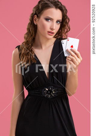 Young woman holding two aces in hand against on pink background Young woman holding two aces in hand against on pink background 92520928