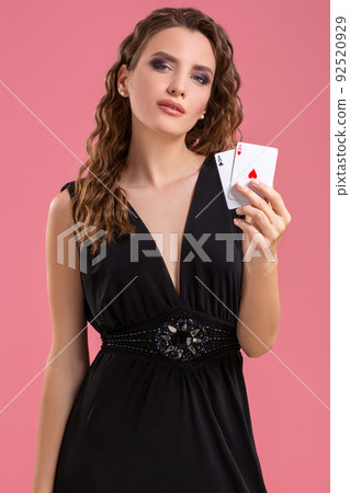 Young woman holding two aces in hand against on pink background Young woman holding two aces in hand against on pink background 92520929