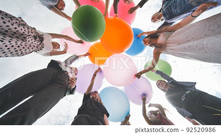 Cheerful girlfriends connect large colorful balls in a circle. Cheerful girlfriends connect large colorful balls in a circle. 92520986