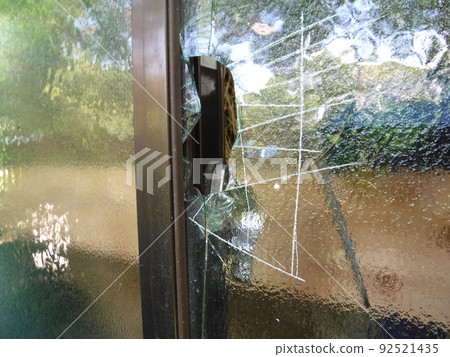 Glass window broken by a thief 92521435