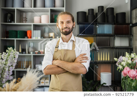 Man florist at his own floral shop taking care of flowers. Man florist at his own floral shop taking care of flowers. 92521779