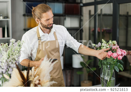 Man florist at her own floral shop taking care of flowers. Man florist at her own floral shop taking care of flowers. 92521813