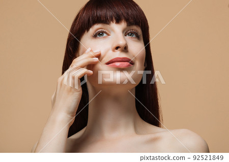 Portrait of caucasian young woman with red hair and healthy skin touches her cheek with fingers Portrait of caucasian young woman with red hair and healthy skin touches her cheek with fingers 92521849